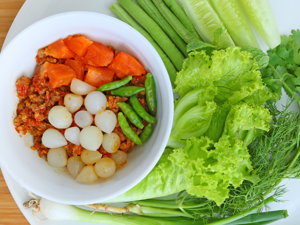 Northern Thai spicy tomato dip, Nam Prik Ong, served with fresh vegetables and crispy pork rinds.