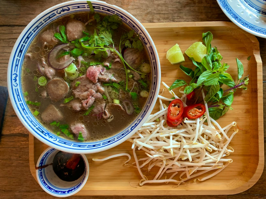 A steaming bowl of Pho, the national dish of Vietnam, served with fresh herbs and lime.