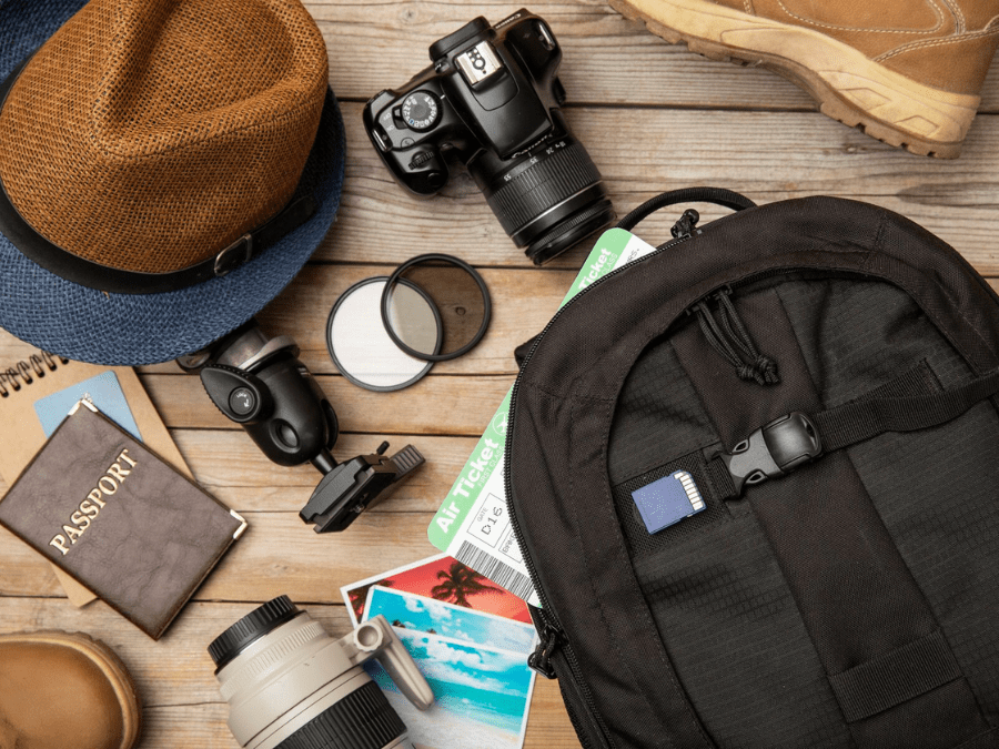 Essential travel accessories including a backpack, reusable water bottle, sunglasses, and hat.