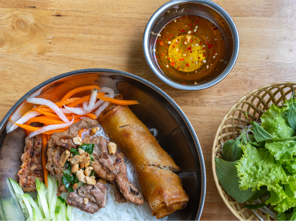 A bowl of Bun Thit Nuong with grilled pork, fresh herbs, and peanuts