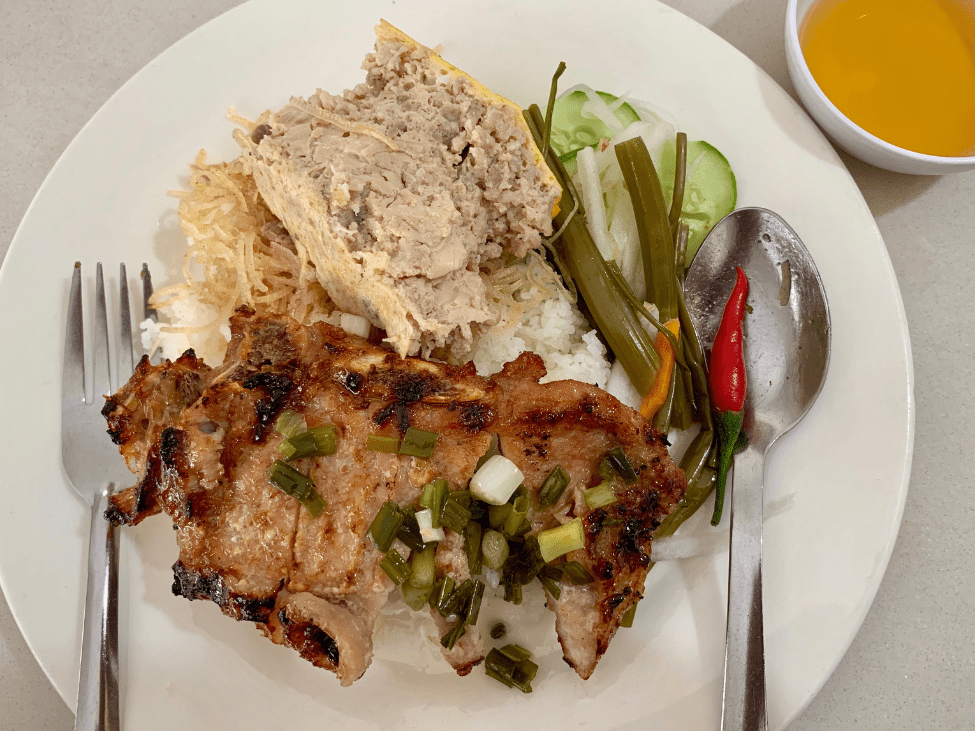 A plate of Com Tam with grilled pork, pickled vegetables, and a fried egg