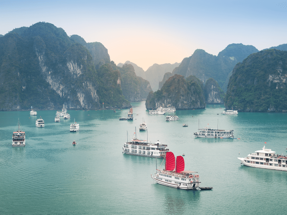 Misty Ha Long Bay with limestone karsts and cruise boats during the monsoon season