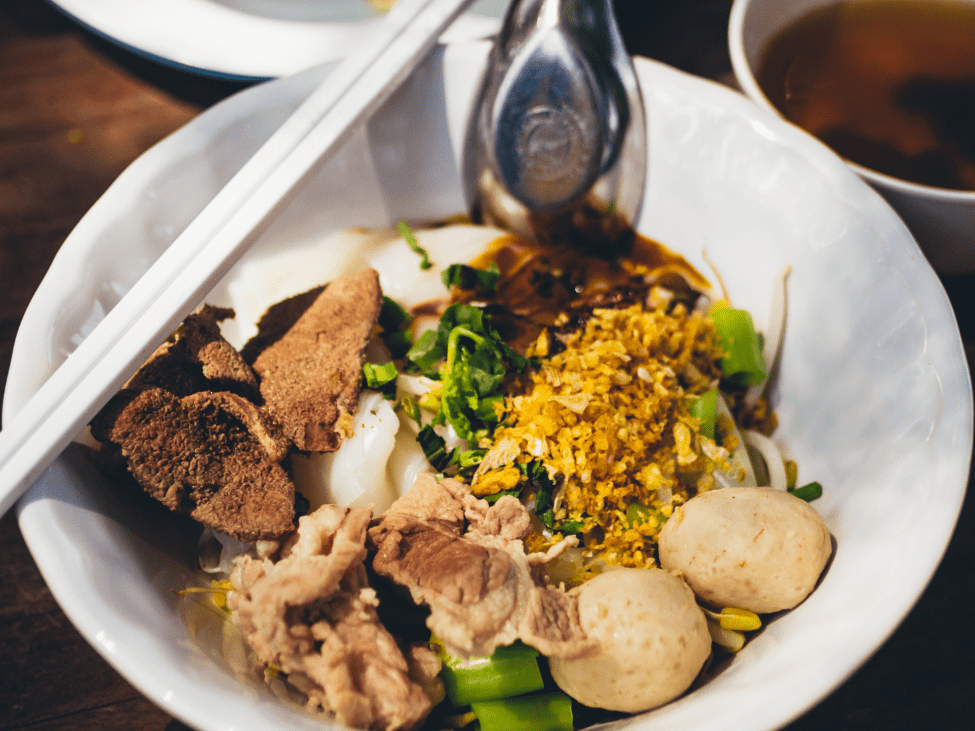 A bowl of Hu Tieu with seafood and fresh herbs