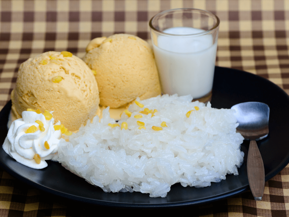 A bowl of Kem Xôi with sticky rice topped with coconut ice cream.