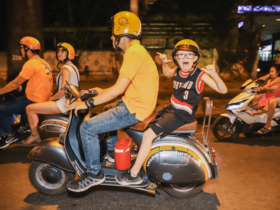 Kids enjoying a Vespa ride through the streets of Hanoi.