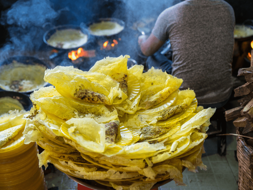 Crispy Banh Xeo pancake filled with shrimp and bean sprouts on a plate.