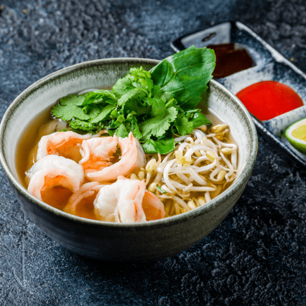 A bowl of fusion pho topped with tender beef and succulent shrimp, showcasing a modern twist on the classic Vietnamese dish.