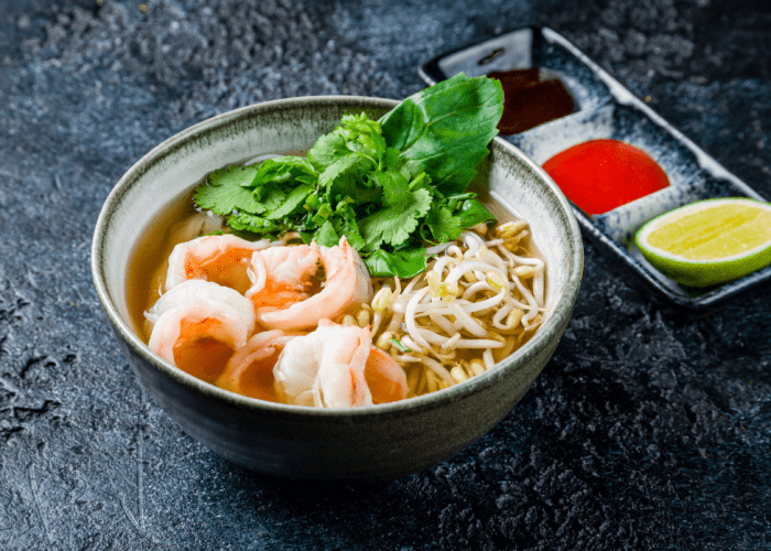 A bowl of fusion pho topped with tender beef and succulent shrimp, showcasing a modern twist on the classic Vietnamese dish.