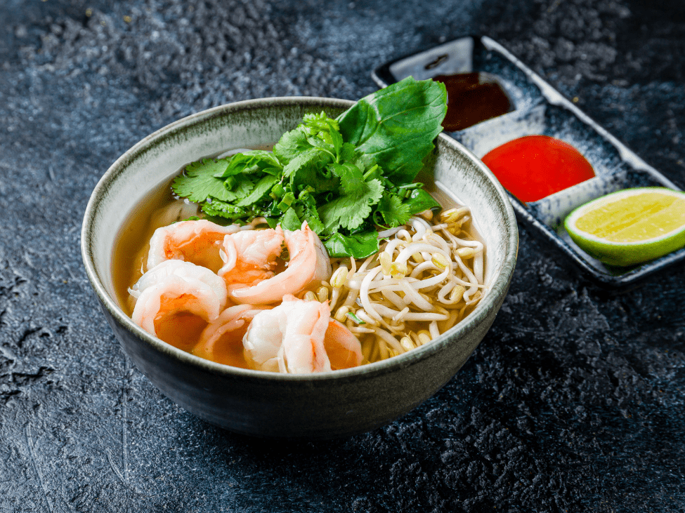 A bowl of fusion pho topped with tender beef and succulent shrimp, showcasing a modern twist on the classic Vietnamese dish.