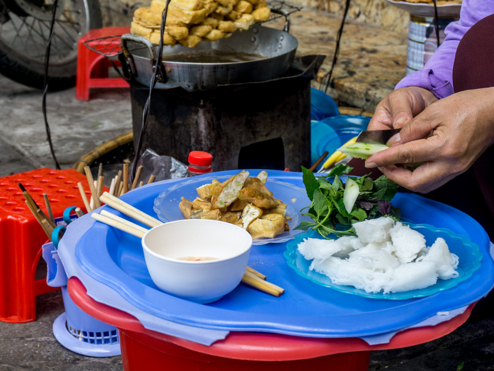 A bustling Hanoi street food tour with locals enjoying traditional dishes.