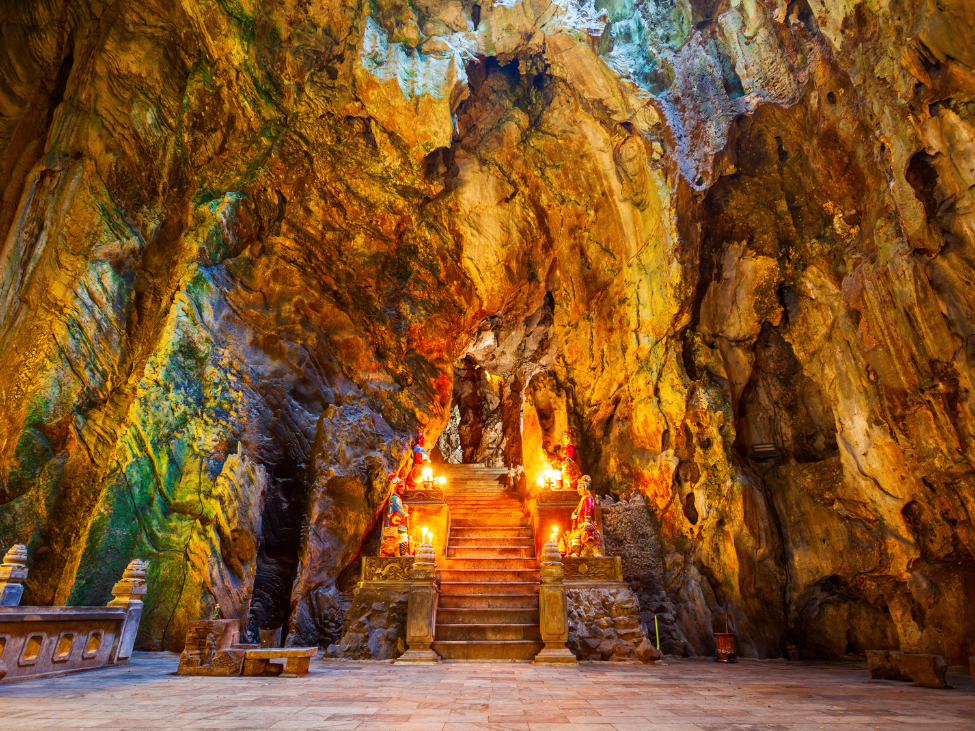 Sunlight illuminating Buddha statues inside the mystical Huyen Khong Cave in Marble Mountains, Da Nang.