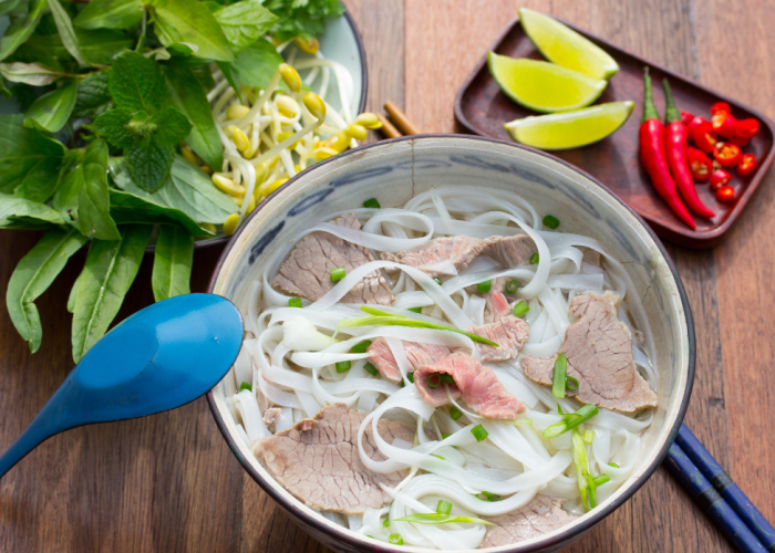 A steaming bowl of pho viet with fresh herbs and noodles, served at Superior Pho.