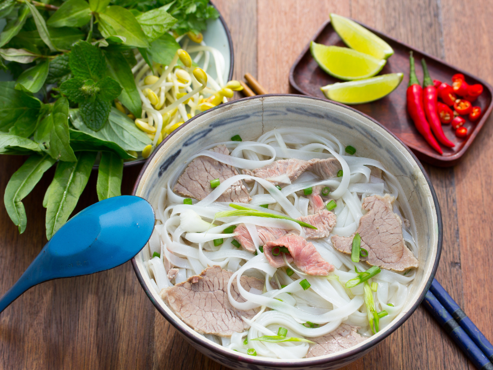 A steaming bowl of pho viet with fresh herbs and noodles, served at Superior Pho.