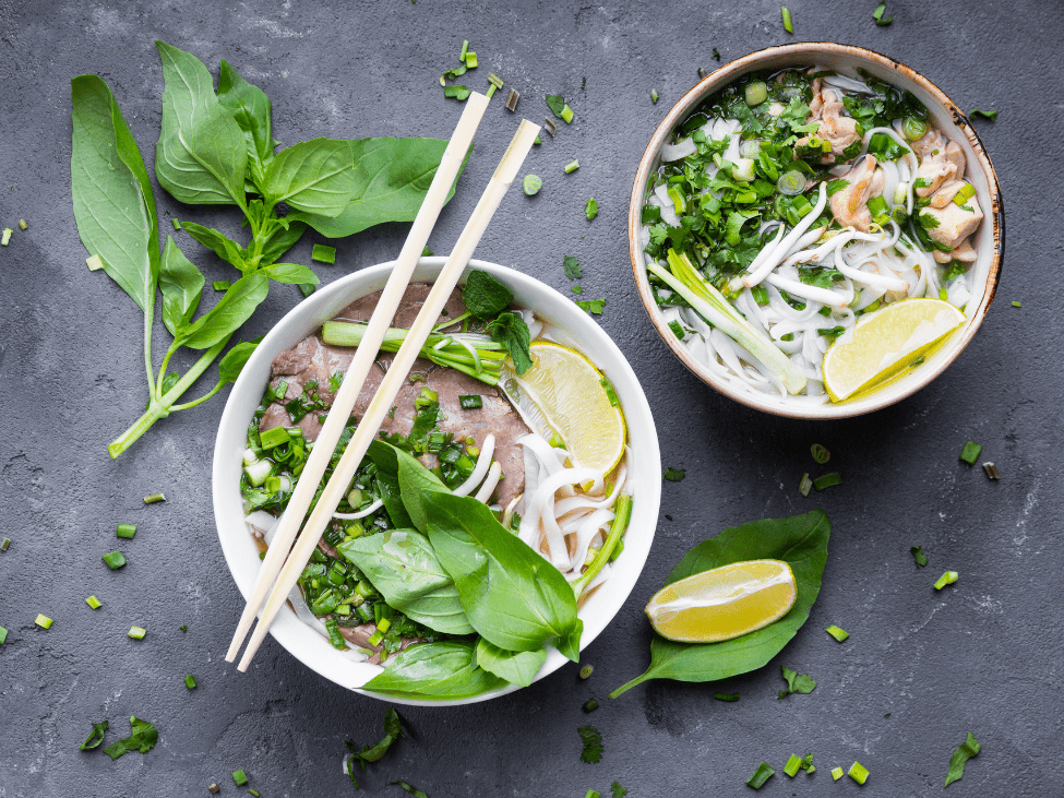 A steaming bowl of vegetarian fusion pho with tofu and fresh herbs, blending traditional flavors with a creative twist.