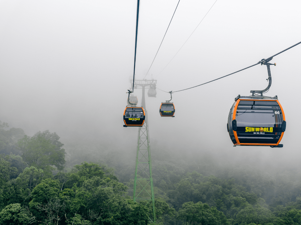 Aerial view of Ba Na Hills cable car traveling over lush mountains.