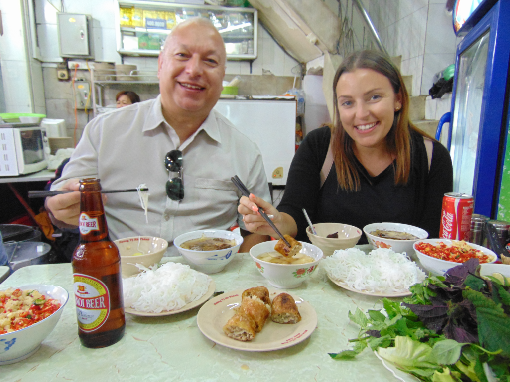 A local guide serving Bún Chả to tourists during a Vespa tour in Hanoi.