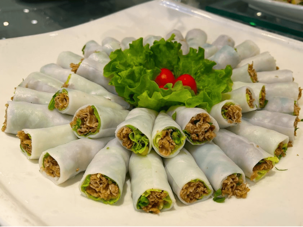 Pho cuon roll being dipped into a savory-sweet sauce at Phở Cuốn Duy Mập.