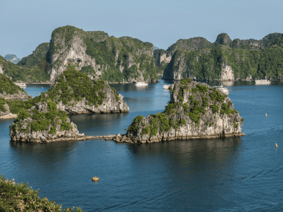 Emerald green waters of Ha Long Bay with limestone islets and misty horizons.