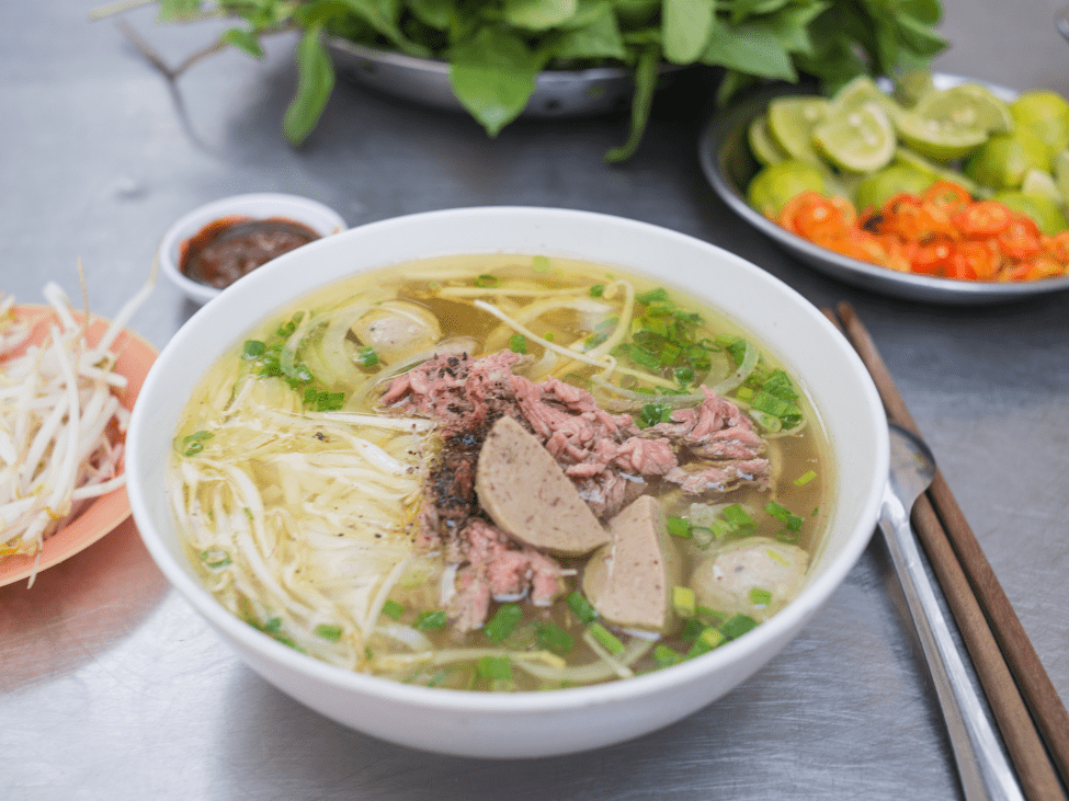 A steaming bowl of Hanoi-style pho with tender beef slices and fresh herbs.