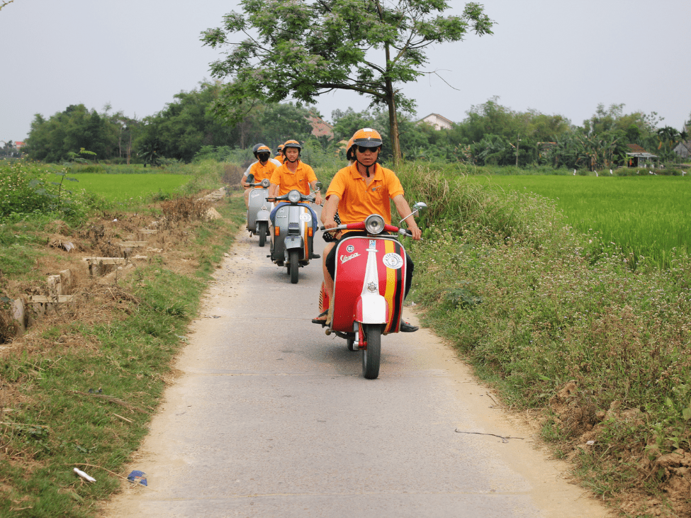 A traveler on a Vespa, exploring the scenic countryside of Hoi An during the Countryside & Islands Explorer tour.