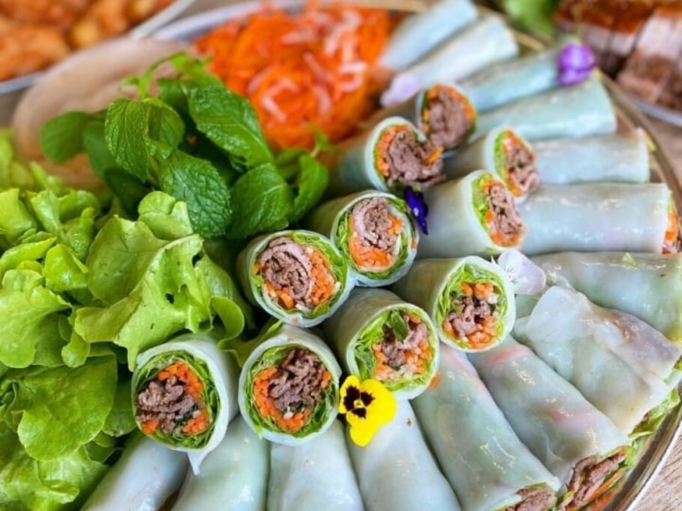 Diners enjoying pho cuon at Phở Cuốn Hưng Bền, with a variety of dishes on the table.