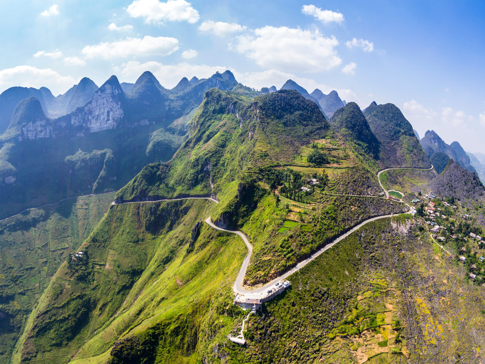 The winding road of Ma Pi Leng Pass with deep valleys and river views.