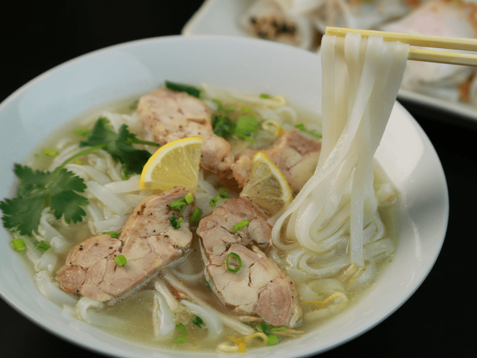 A comparison of Pho Bo (beef) and Pho Ga (chicken) with traditional Vietnamese garnishes.