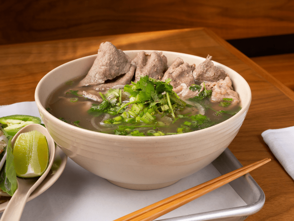 Bowl of pho served at Pho Cambridge with fresh herbs.