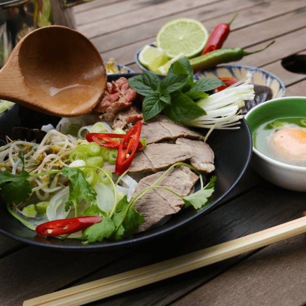 A bowl of Southern-style pho at Phở Tau Bay, garnished with fresh herbs and lime.