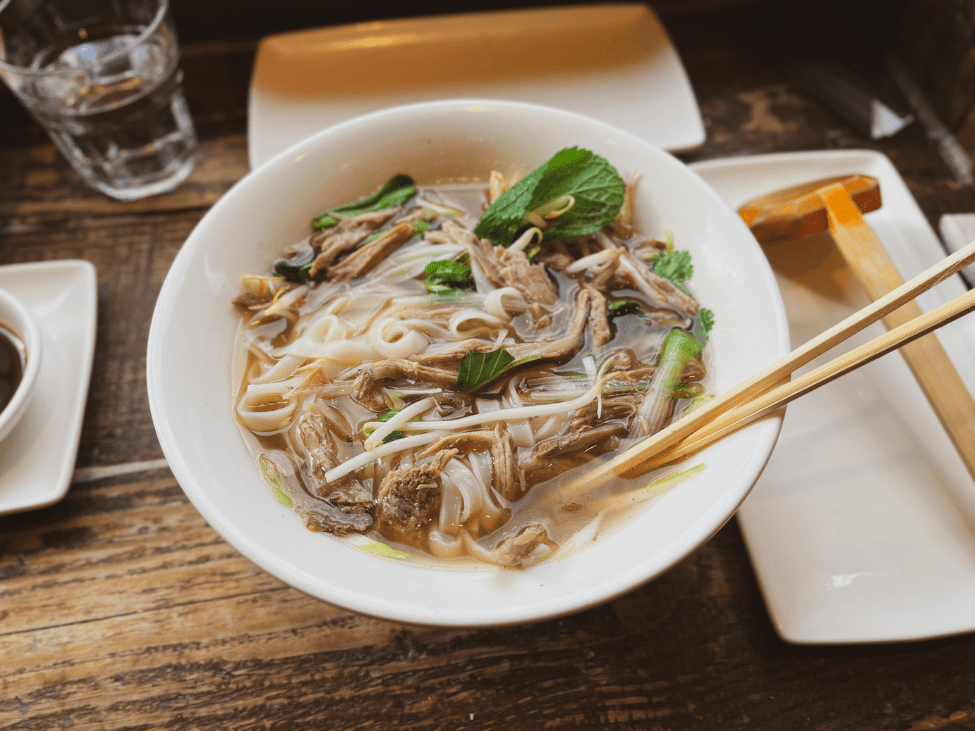 A delightful bowl of authentic Vietnamese pho at Pho Stop in Singapore, brimming with fresh herbs and tender beef.