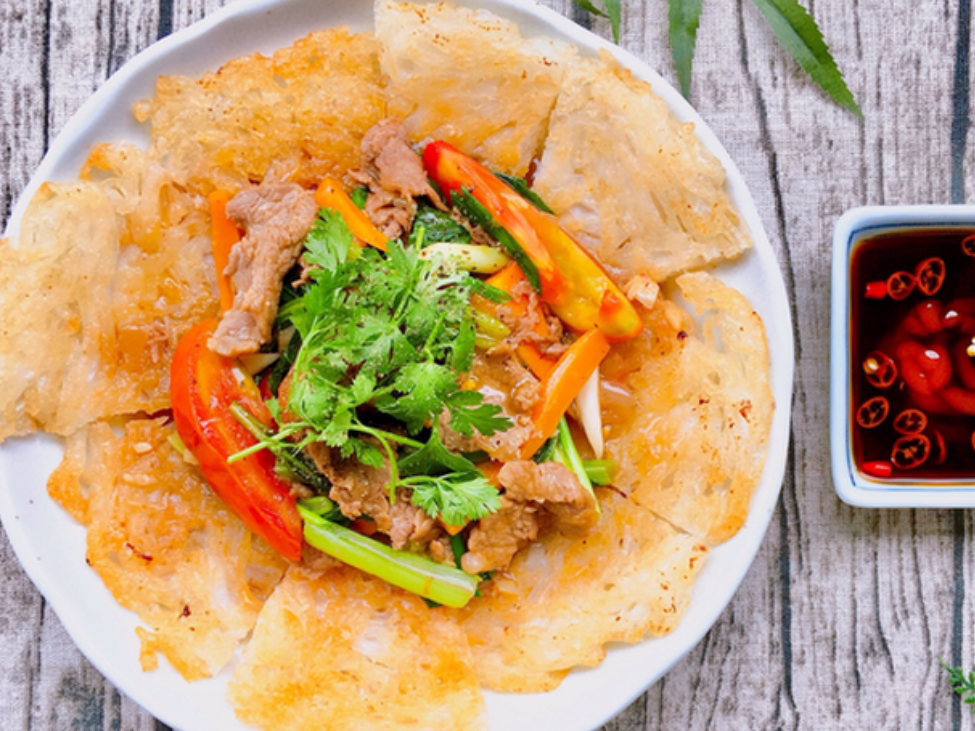 A plate of crispy Phở Áp Chảo with beef and stir-fry sauce at Vọng Hà