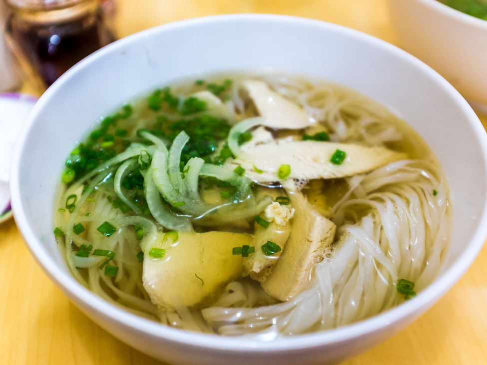 A vibrant bowl of Saigon-style pho with fresh herbs and thin noodles.