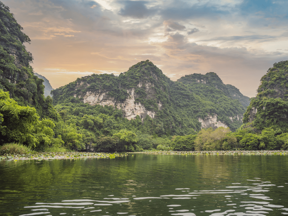 Boats floating through the serene waters of Trang An Landscape Complex surrounded by towering limestone cliffs.