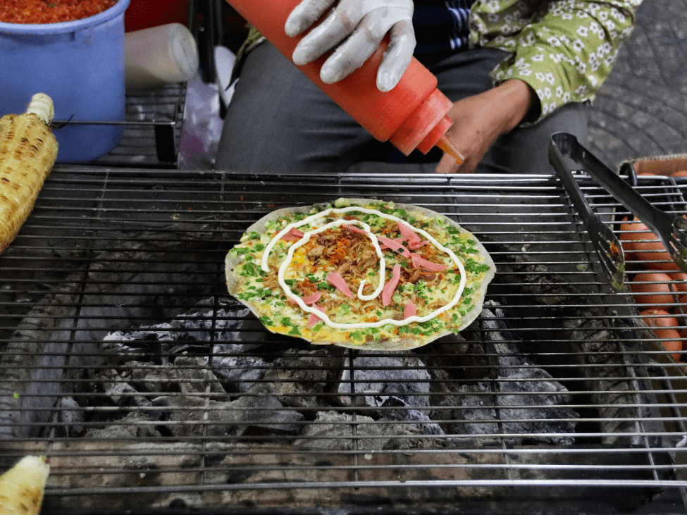 Vietnamese Bánh Tráng Nướng, also known as Vietnamese pizza, on a grill.