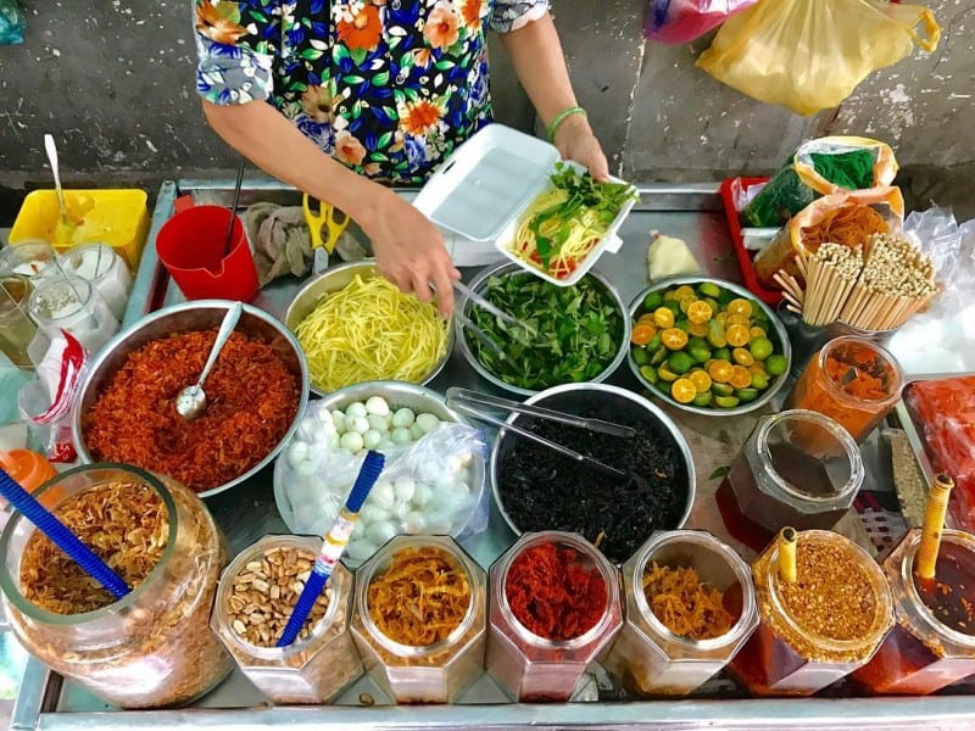 Ingredients for Bánh Tráng Trộn including rice paper, dried shrimp, mango, and herbs