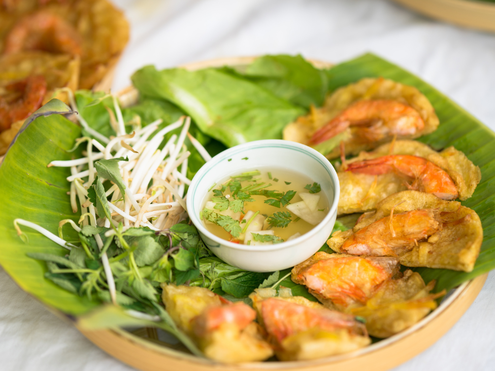 Crispy Banh Xeo pancakes filled with shrimp and pork, served with herbs