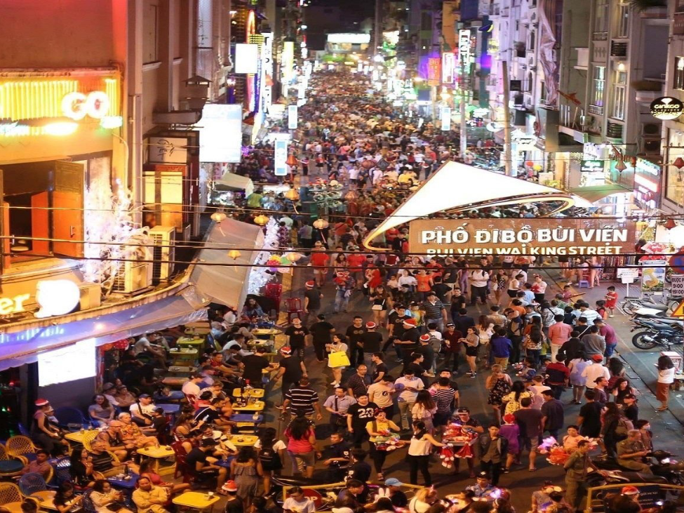 Bustling nightlife on Bui Vien Street with neon signs and street food vendors.