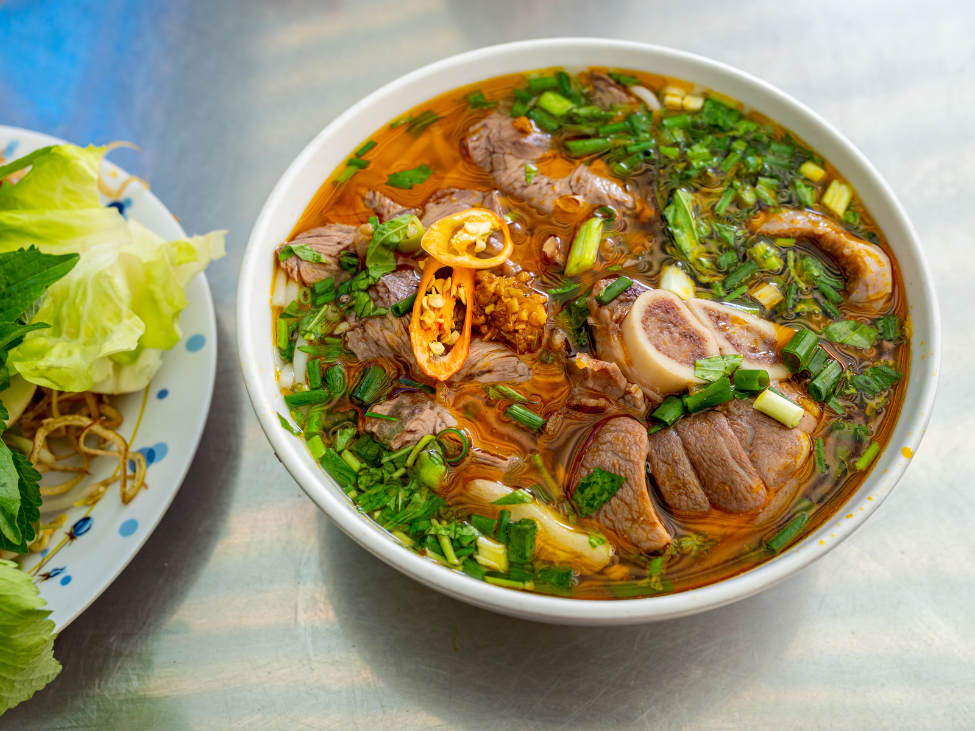 A spicy bowl of Bun Bo Hue with beef shank, round noodles, and lemongrass broth.