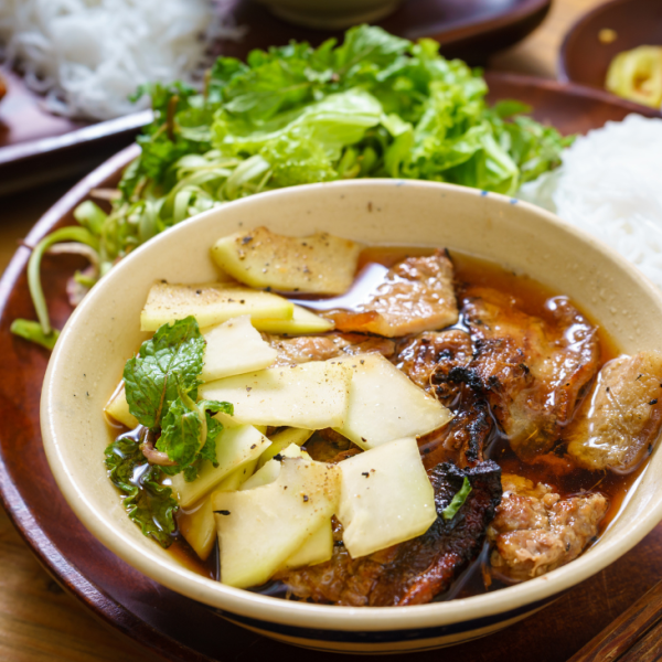 A plate of bún chả with grilled pork, vermicelli, and fresh herbs.