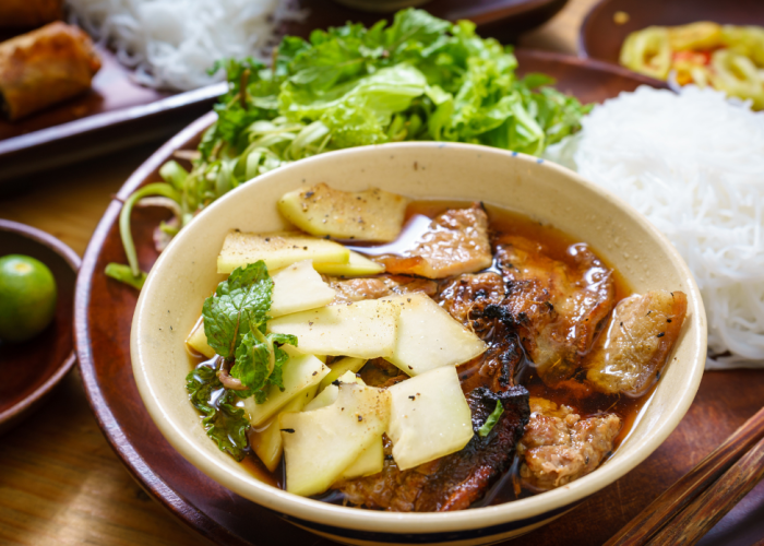 A plate of bún chả with grilled pork, vermicelli, and fresh herbs.