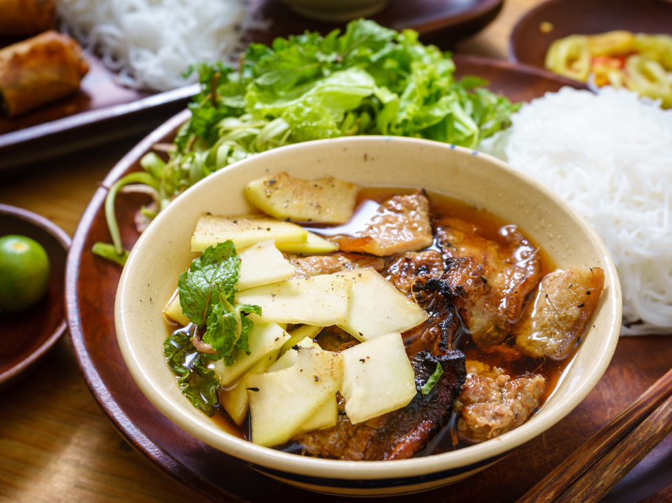 A plate of bún chả with grilled pork, vermicelli, and fresh herbs.