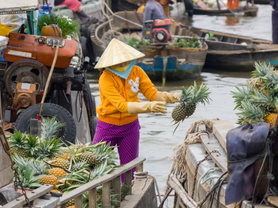 olorful boats filled with fruits and vegetables at Cai Be Floating Market in the Mekong Delta.