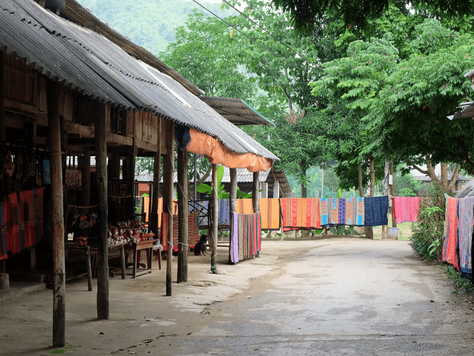 Traditional stilt houses of the Ede people surrounded by lush green forests in the Central Highlands of Vietnam.