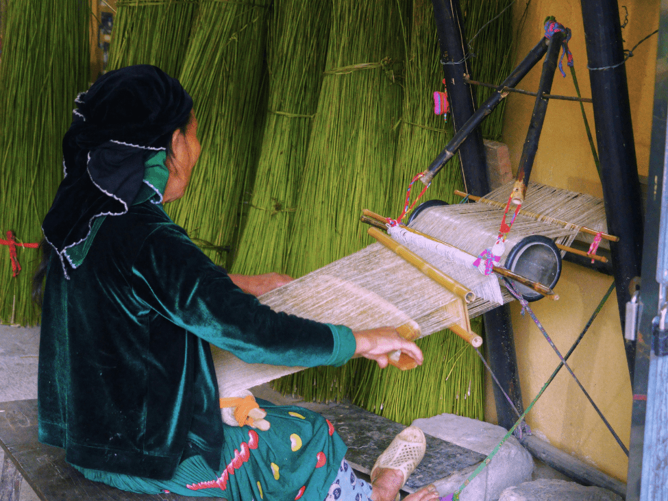 A woman weaving fabric on a traditional loom in a Cham craft village in Hoi An.