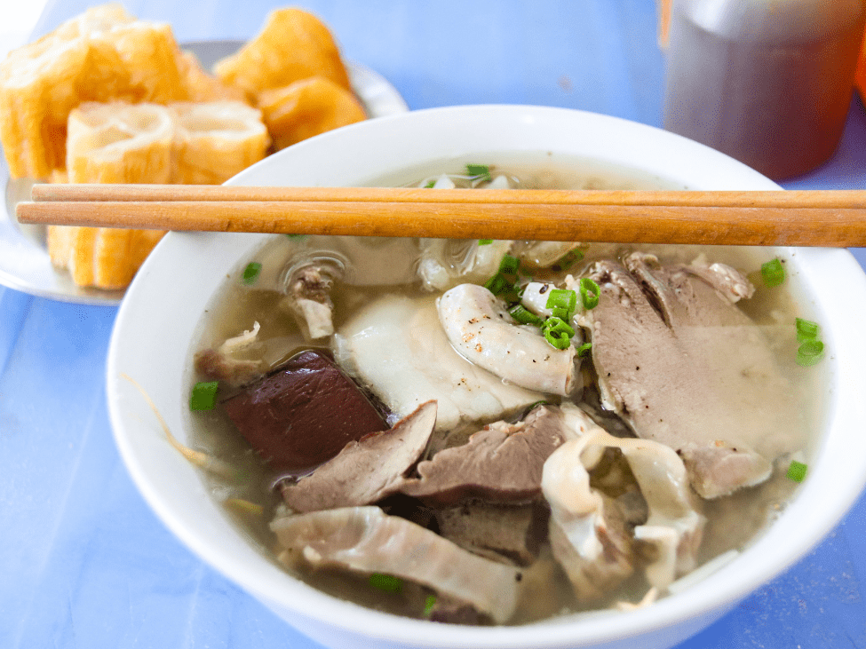 A bowl of cháo rice porridge with shredded chicken and herbs.