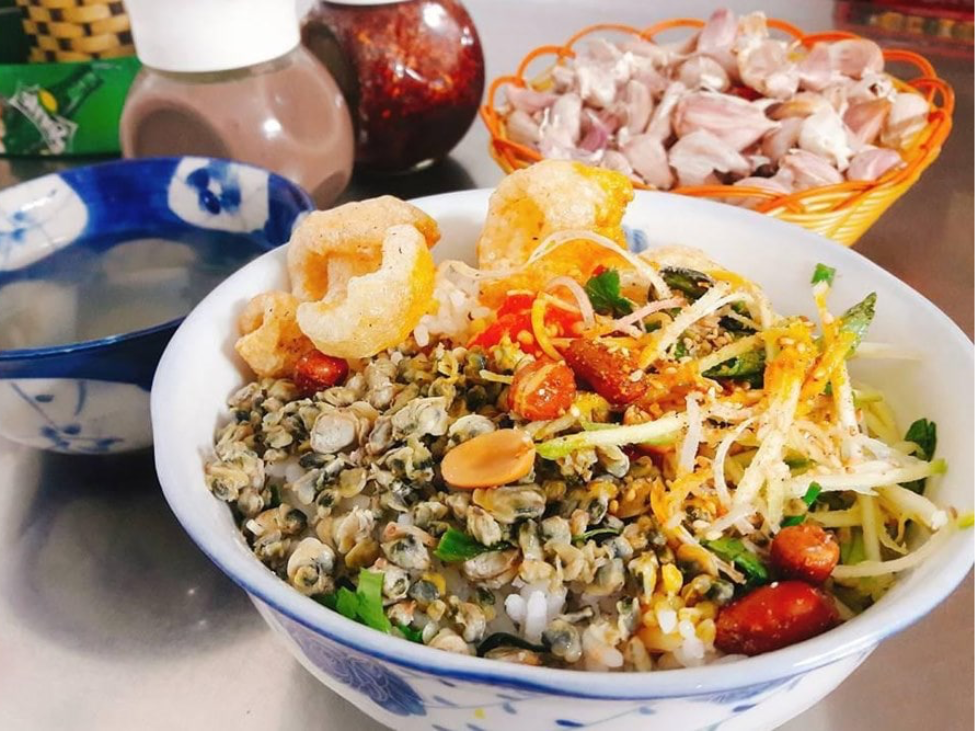 A bowl of Com Hen with clams, herbs, and crispy pork skin