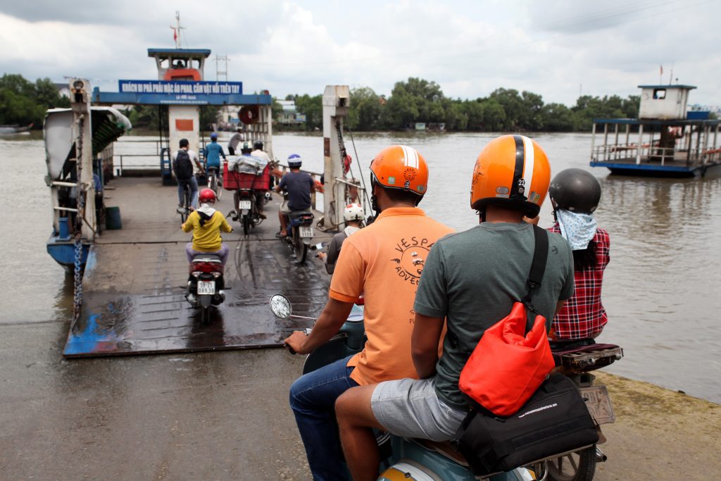 A group of travelers on vintage Vespas exploring a local village in the Mekong Delta from Ho Chi Minh.