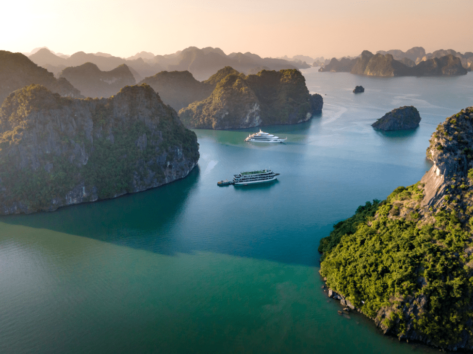 Traditional junk boats sailing through the emerald waters of Ha Long Bay.