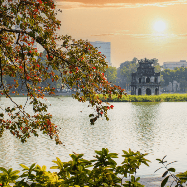 Autumn leaves reflecting on the serene waters of Hoan Kiem Lake in Hanoi.