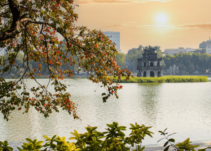 Autumn leaves reflecting on the serene waters of Hoan Kiem Lake in Hanoi.